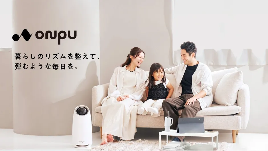 家族3人がリビングのソファで笑顔でくつろいでいる様子が写った画像。白を基調とした部屋で、空気清浄機らしきものも置かれている。