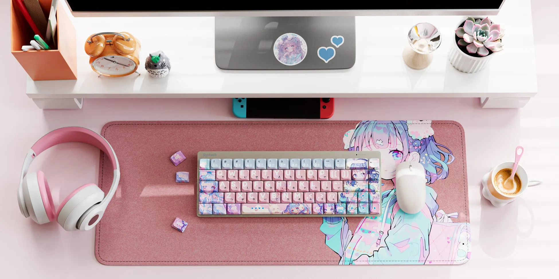 ピンク色のデスク周りの写真。キーボード、マウス、ヘッドホン、時計、多肉植物、カップ、Switchなどが写っている。