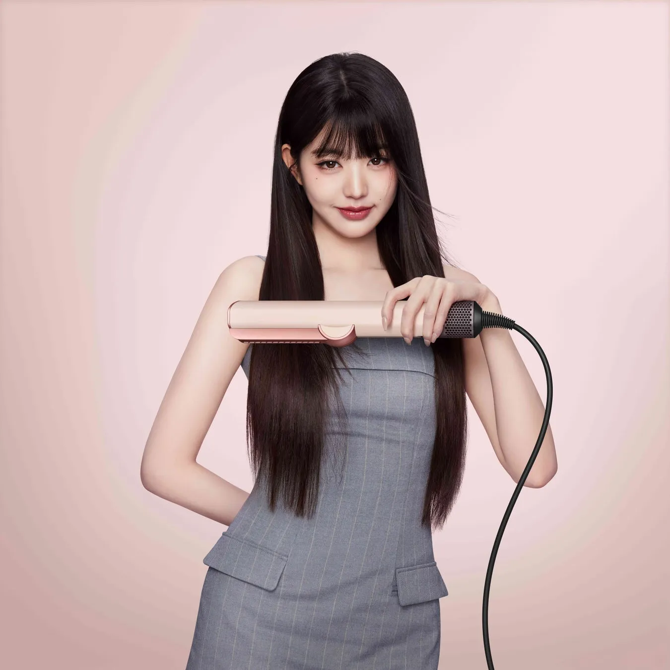 女性がヘアアイロンを持って微笑んでいる様子